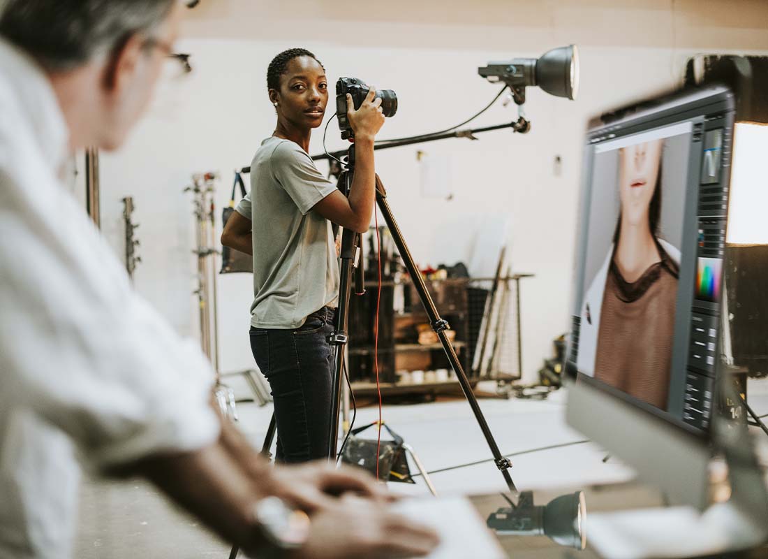 Professional Services Insurance - Checking Photos From a Studio Photo Shoot With Photographer Standing at Her Camera and Getting Ready for a Second Session