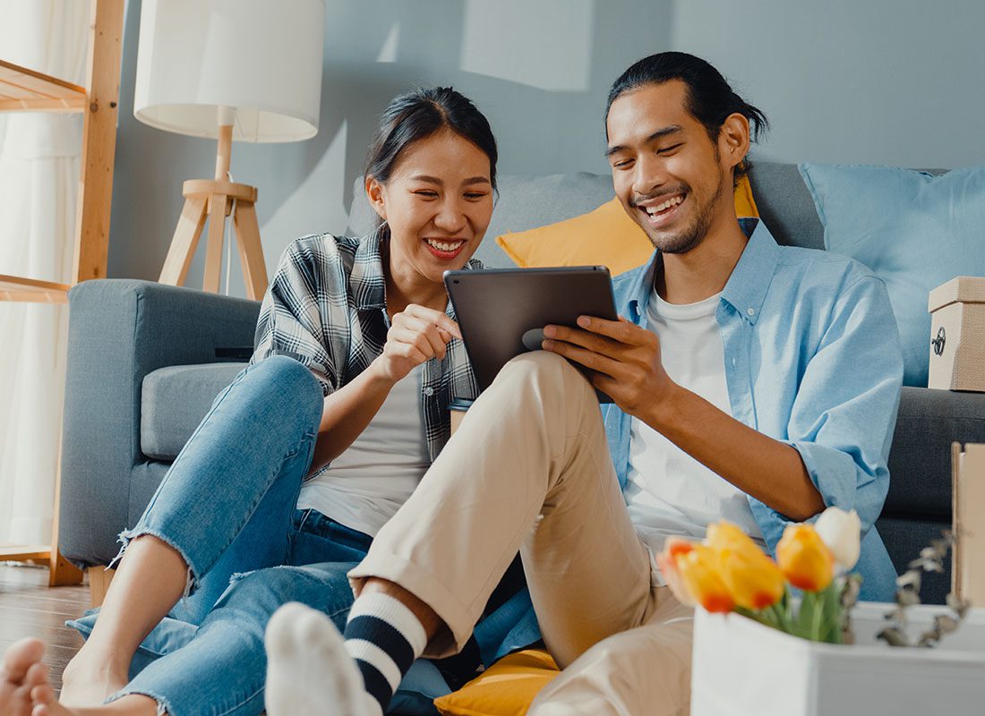 Contact - Happy Couple Using a Tablet to Access Their Insurance Account Information After Moving Into a New House